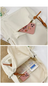 Detail view of cream white backpack featuring multi-pocket compartments and mesh divider