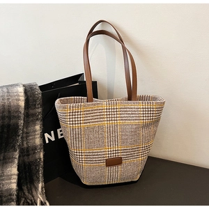 Dettaglio della borsa pied-de-poule vintage con toppa in pelle marrone e trama in tessuto spesso