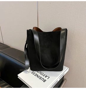 Detail of black faux suede bucket bag with smooth leather handle and caramel interior