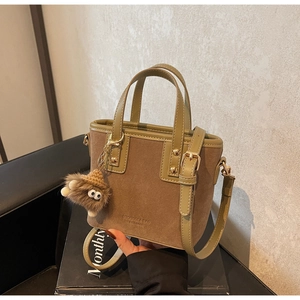 Détail du mini sac cabas avec poignées en cuir vert et un pendentif peluche