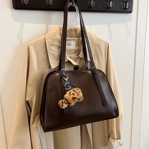 Détail d'un sac cabas en similicuir marron foncé avec un pompon léopard tendance