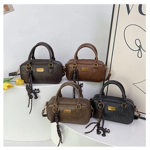 Detailed macro view of stylish retro Boston bags with chic cat charms and gold hardware