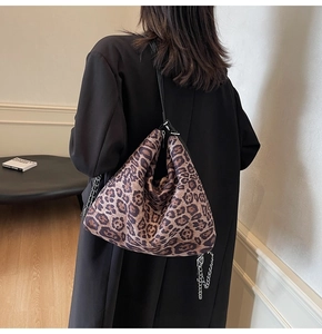 Detail of leopard print hobo bag with silver chain and black strap on black coat