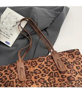 Détail des bretelles marron et des renforts en cuir sur le sac fourre-tout à motif léopard