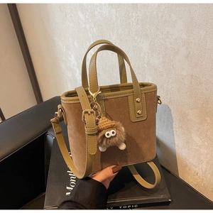 Détail du mini sac seau en daim bicolore avec un pendentif peluche amovible