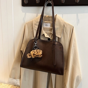 Détail d'un sac à bandoulière en cuir PU marron foncé avec charm en peluche