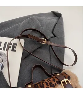 Détail de la bandoulière réglable en cuir avec boucle en métal sur le sac à motif léopard