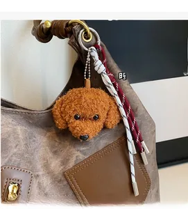 Plush brown poodle bag charm with braided tassel on a leather tote bag detail