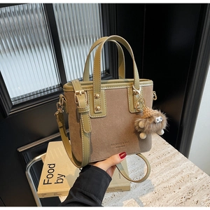 Détail des finitions en cuir vert olive et sac seau en daim marron avec breloque peluche
