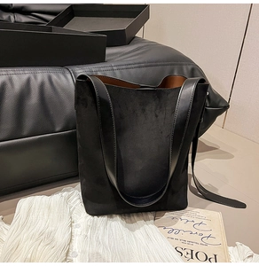 Detail view of large black faux suede bucket bag with contrast leather shoulder strap