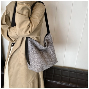 Detail of grey knitted shoulder bag with black strap worn with camel coat style
