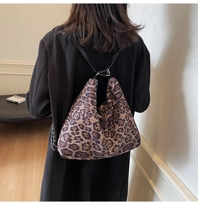 Detail of leopard print tote bag with black leather strap and metallic buckle hardware