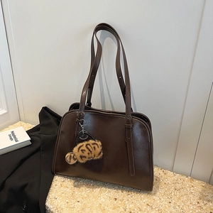 Détail d'un sac cabas vintage en similicuir marron foncé avec un charme en peluche léopard