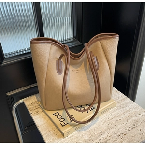 Detail of beige lychee texture tote bag with dark brown edges and sleek shoulder straps