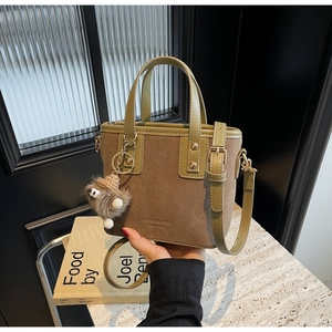 Détail du sac fourre-tout bicolore vert et marron avec logo et charm peluche monstre