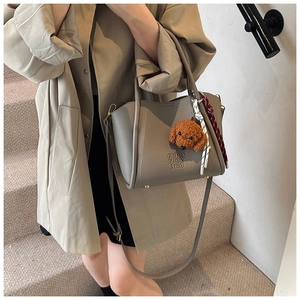 Détail du sac seau gris texturé avec gaufrage et breloque chien en peluche marron