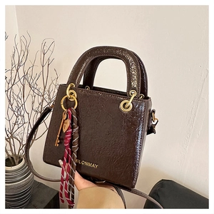 Detailed close-up of brown crinkled leather handbag with gold logo and key pendant