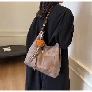 Detail of vintage brown tote bag with rope strap and teddy bear charm on model