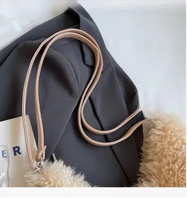Detail of khaki plush tote bag with soft texture and slim shoulder strap on grey blazer