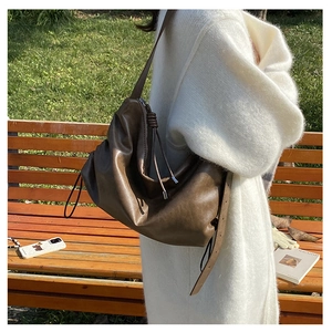 Detail of coffee brown hobo bag with drawstring and zipper on casual shoulder strap
