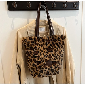 Dettaglio della borsa tote in peluche leopardata con manici in pelle marrone su un trench