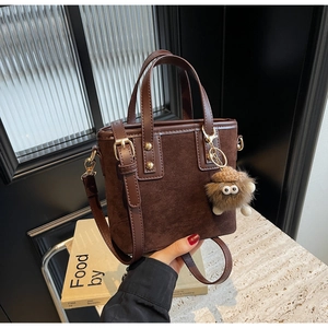 Détail du sac seau marron vintage avec charm pomme de pin en peluche et boucles dorées