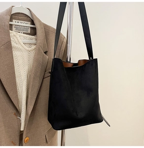 Detail of black faux suede tote bag with contrast caramel lining and long shoulder strap