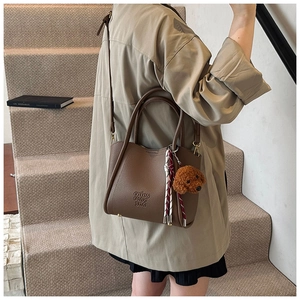 Détail du sac seau en cuir marron café avec breloque ours et foulard en soie décoratif
