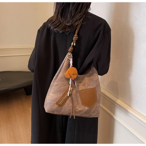 Brown vintage tote bag with knotted strap and teddy charm shown on a female model