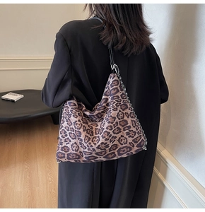 Detail showing oversized leopard print tote bag with metal chain on a female model