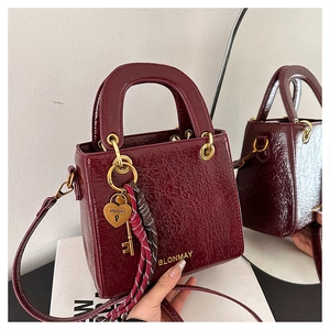 Macro shot of burgundy faux leather square bag with golden heart padlock and silk scarf detail