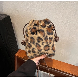 Detail of plush leopard print bucket bag with drawstring closure and leather strap
