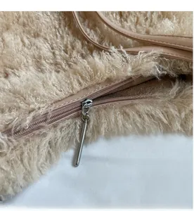 Detail shot of smooth metal zipper closure on beige plush faux fur tote shoulder bag