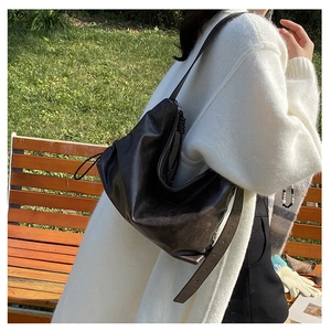 Detail of soft brown hobo bag with adjustable strap and metal eyelets outdoors