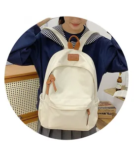 Close-up of white canvas backpack with leather handle and front zipper pocket