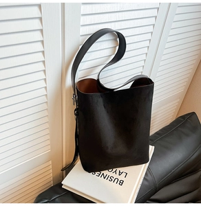 Detail of black suede bucket bag with brown lining and adjustable wide shoulder strap