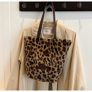 Dettaglio della borsa tote in peluche leopardata con manici in pelle marrone e trama morbida