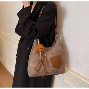 Detail of vintage brown textured tote bag with leather strap and plush dog charm