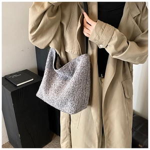 Detail shot of grey fuzzy knit texture and black strap on this autumn bucket shoulder bag