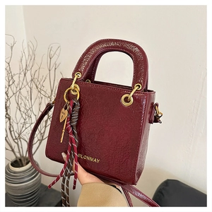 Detailed close-up of dark wine red wrinkled leather texture and golden logo on bag