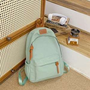 Detail of light green minimalist backpack with brown leather patch and side pockets