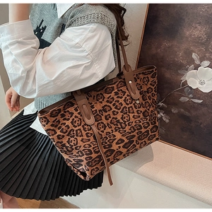 Close-up of leopard print tote bag with brown leather handles worn by a stylish model