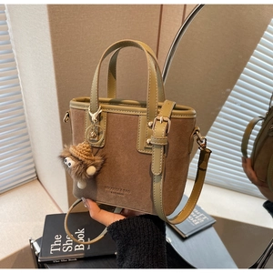 Détail d'un sac seau en cuir vert foncé avec breloque peluche et reflet dans le miroir