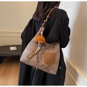 Detail of vintage brown textured crossbody bag with teddy charm and knotted shoulder strap