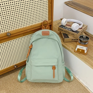 Close-up of mint green school backpack with leather handles and brand label detail