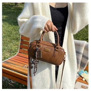 Borsa Boston marrone con ciondoli a forma di gatto e cioccolato in contesto outdoor
