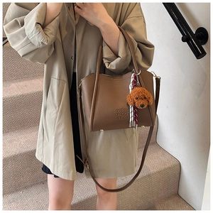 Détail du sac seau marron avec grain litchi, breloque doudou et logo embossé