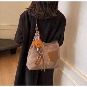 Rear view of brown vintage texture tote bag with tassel zipper and plush dog charm