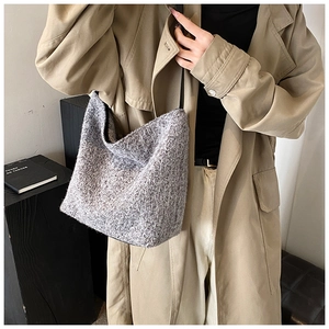 Detail of grey knitted hobo shoulder bag with textured tweed fabric and slim black strap