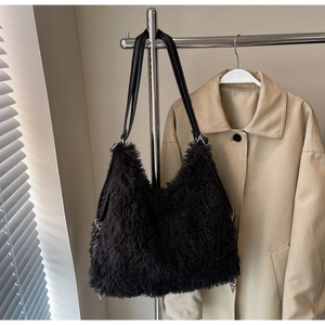 Detailed view of black plush shoulder bag with faux fur texture and silver ring hardware